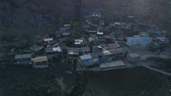 Aerial tilt down and lift up over volcano village Pozo de Las Calcosas