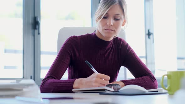 Serious businesswoman writing in notebook