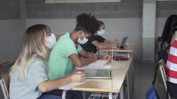 Secondary School Students with Face Mask Writing Notes During Lesson in a High School Classroom