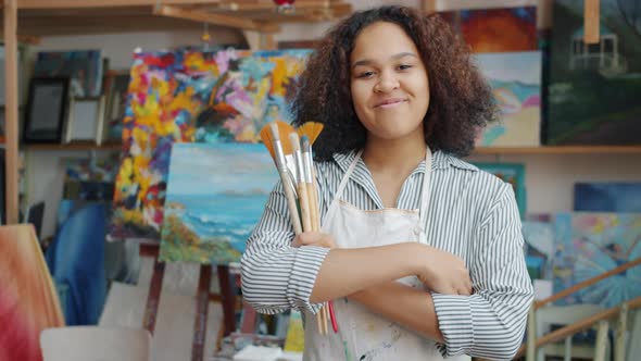 Portrait of Beautiful Afro-American Woman Standing in Art Class Holding Brushes