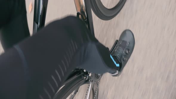 Cycling man legs pedaling on road bicycle. Strong sportive cyclist legs in black pedaling a bike
