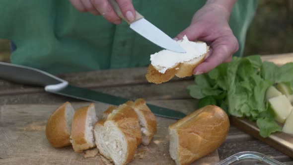 Stylish woman make a snack with bread and cheese on a table in outdoor