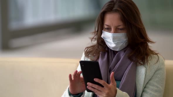 Close-up Portrait of a Dark-haired Woman Sitting in the Waiting Room, Wearing a Protective Mask. She