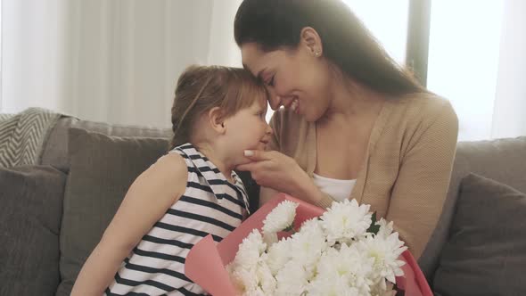 Little Daughter Congratulates Mother and Gives Heart Memory Card and White Flowers