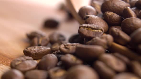 Full rustic wooden spoon of roasted coffee beans. Falling Arabica grains on a wooden surface