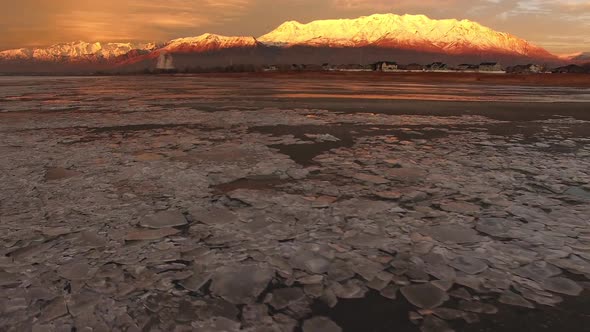 Flying over ice chunks viewing reflection of snow capped mountain