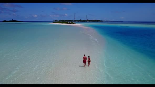 Two people posing on marine tourist beach trip by blue lagoon with white sandy background of the Mal