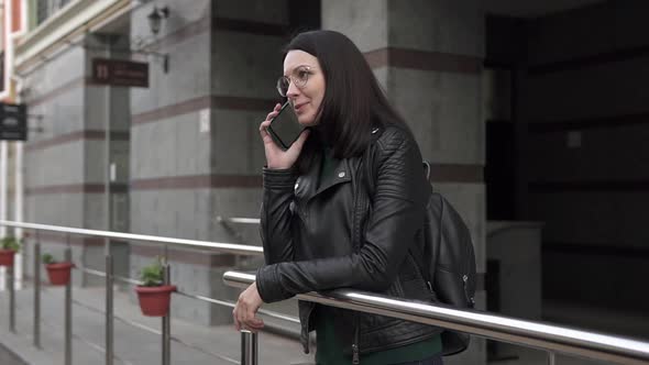 A beautiful European girl talking on the phone in a big city.