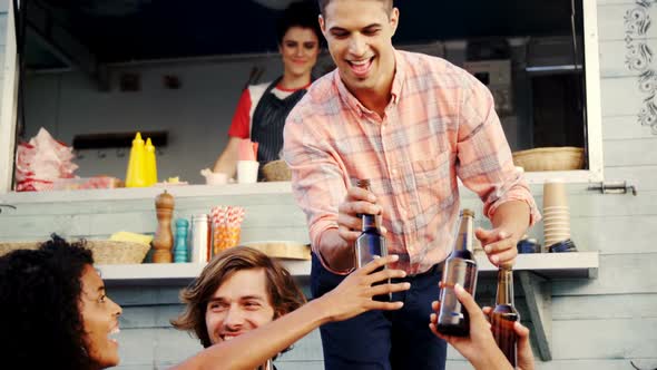 Group of friends toasting beer bottle while having meal