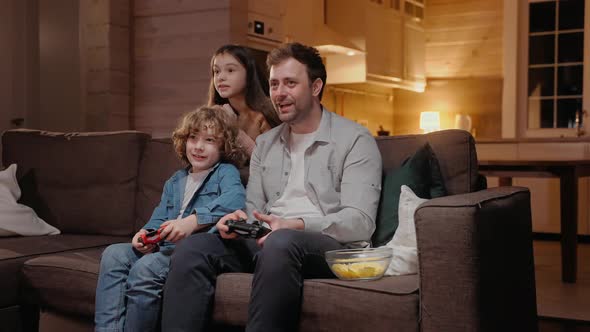 Father Playing with His Son in Game Console and Losing Laughing Sitting on Sofa