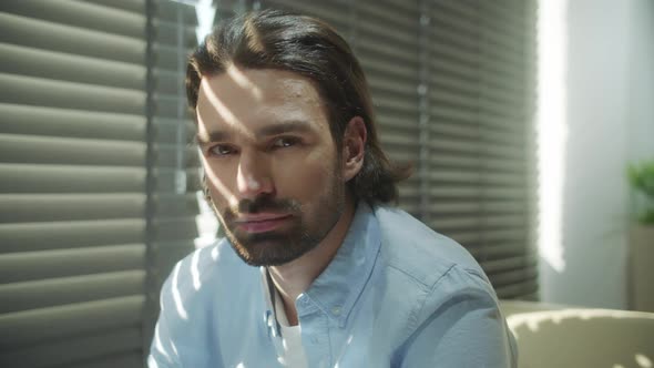 A Young Serious Man is Sitting on the Sofa and Looking Away