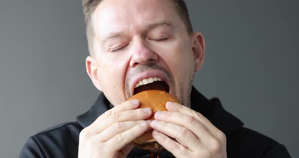 Young Man Eating Delicious Appetizing Hamburger and Enjoying  Movie Slow Motion