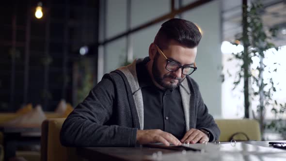 Stylish Guy with Beard in Glasses Came in Restaurant and Choosing Food in Menu