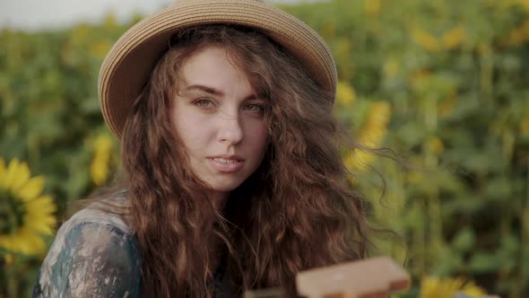 Portrait of Beautiful Curlyhaired Lady Looking at Camera When Painting