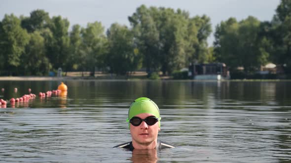 Professional Swimmer in the Lake on a Sunny Day. Only the Athlete’s Head Is Visible Above the