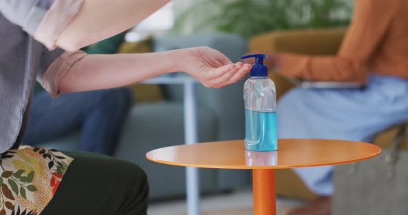 Mid section of woman sanitizing her hands at office