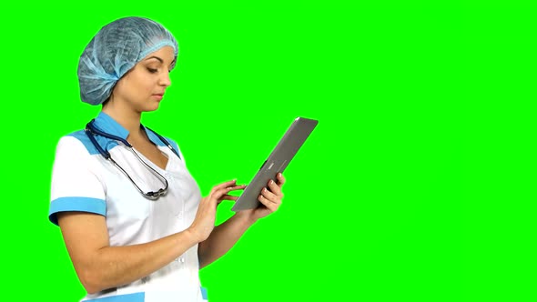 Young Female Medical Nurse Using Tablet Computer on Green Screen