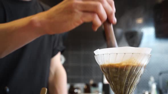 Cinemagraph of specialty coffee barista brewing V60 filter coffee, stirring with wooden stick on loo