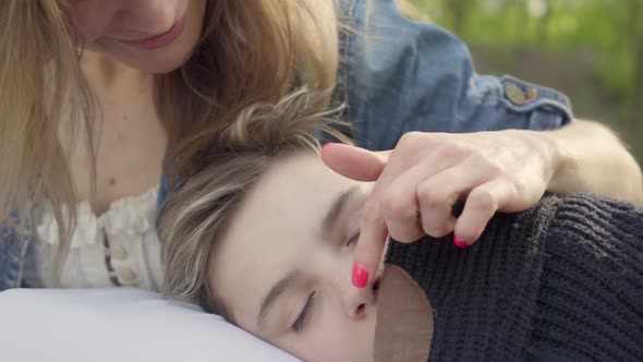 Portrait Pretty Boy Sleeping in Mother's Hands, the Woman Caress Hair of Her Child in the Park