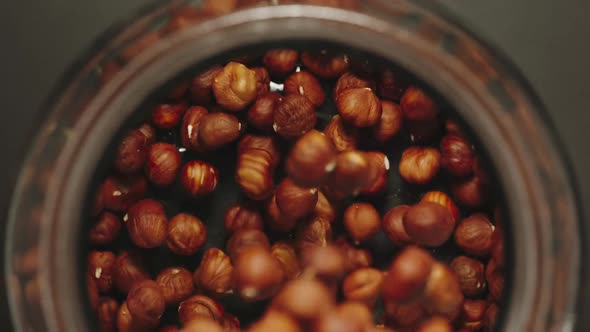 TOP VIEW: Peeled Nuts Falling Into A Glass Jar - Slow Motion