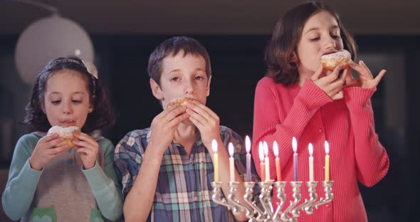 Kids and their mother eating donuts with a menora and dreidels