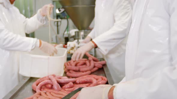 Butchers packing sausages in container