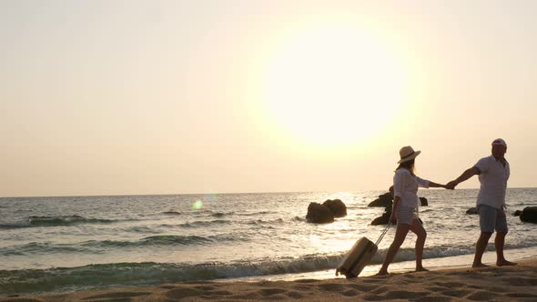 Romantic Couple of Lovers, Silhouettes. Travelers Walk Along the Beach, Holding Hands, with Travel