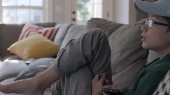 a cute boy with a remote control watches tv