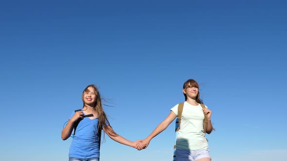 Girls, Women Travelers Go Holding Hands on a Background of Blue Sky. Close-up. Teamwork Tourists