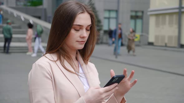 Portrait of Pretty Business Woman Typing By Mobilephone Outdoors at City Street