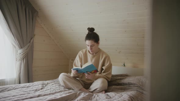 Concentrated woman reading a book in the bedroom