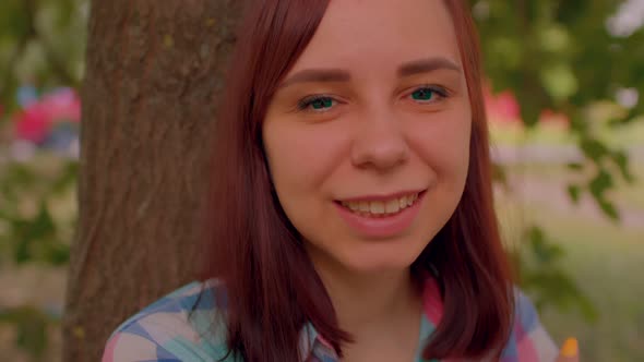 Close Up of Young Woman Smiles and Looks at Camera