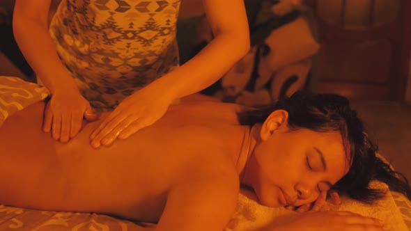 Mixed Race Ecuadorian Woman Enjoying Body Massage in Spa Salon with Candle Light