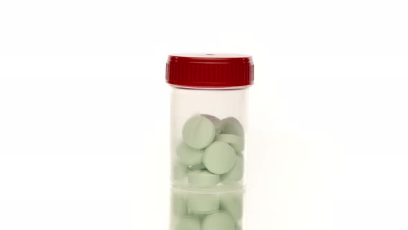 Transparent Pills Bottle with Large Green Pills Isolated on White 360 Rotating