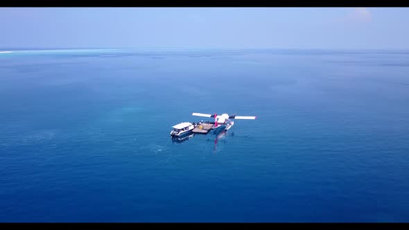 Aerial flying over texture of idyllic lagoon beach lifestyle by blue water and white sandy backgroun