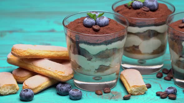 Classic Tiramisu Dessert in a Glass with Blueberries on Blue Wooden Background
