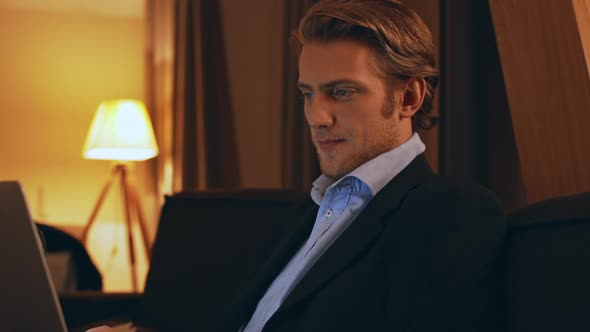 Young Handsome Caucasian Male in Business Suit Sitting at Room Working on Laptop in Slowmotion