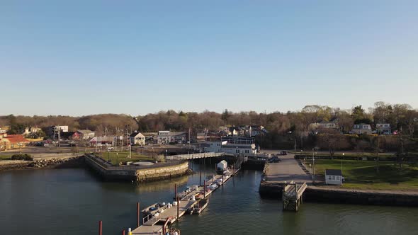 Drone retreat from dock in a coastal village, just as a police SUV pulls onto the pier and drives to