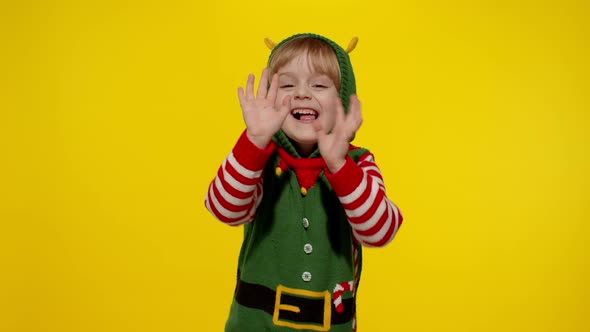 Scared Kid Girl in Christmas Elf Santa Helper Costume Looking Aafraid Hiding Face with Hands