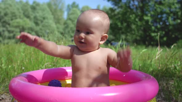 Toddler swims in a small inflatable outdoor pool