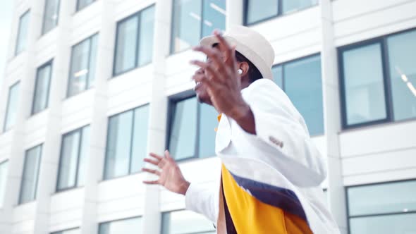 Amazed black dancer guy in white suit and wireless headphones