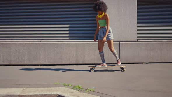 Beautiful young woman cruising around the city with her longboard.