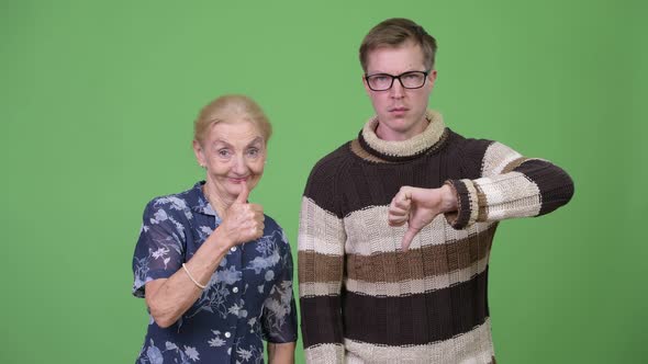 Happy Grandmother Giving Thumbs Up While Upset Grandson Giving Thumbs Down