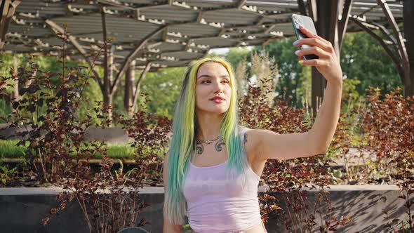 Young Beautiful Girl Makes a Selfie in the City Park