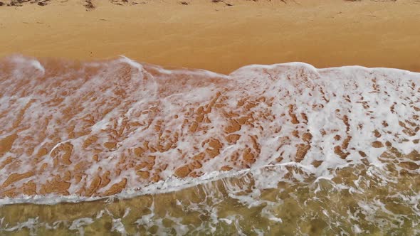 Aerial View of Golden Sandy Beach and Foamy Waves on a Sunny Day