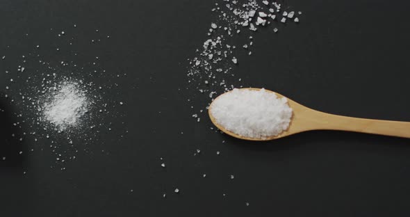 Video of salt in a salt shaker and spoon on black background