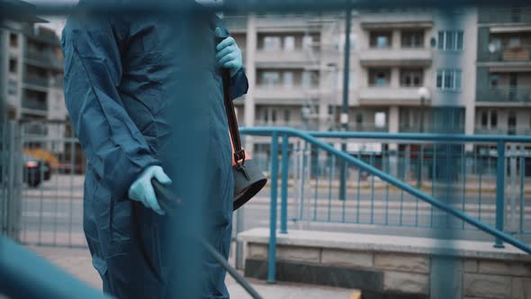 African Man Wearing NBC Personal Protective Equipment Disinfects Stairs in a Public Place