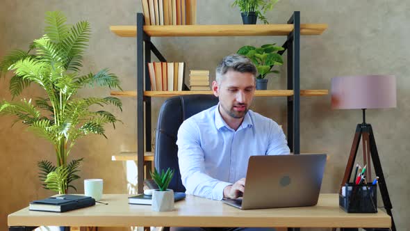 Bearded gray-haired businessman in home office sit on chair at desk open and start using laptop