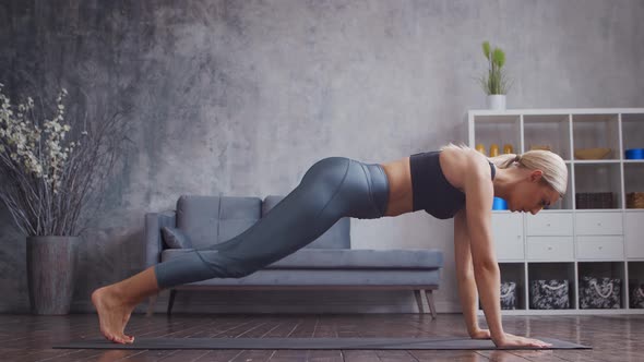 Young and sporty girl in sportswear is doing exercises in home interior.