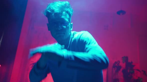 Stylish Dancer Moves to Music in a Smoky Room with Neon Lighting